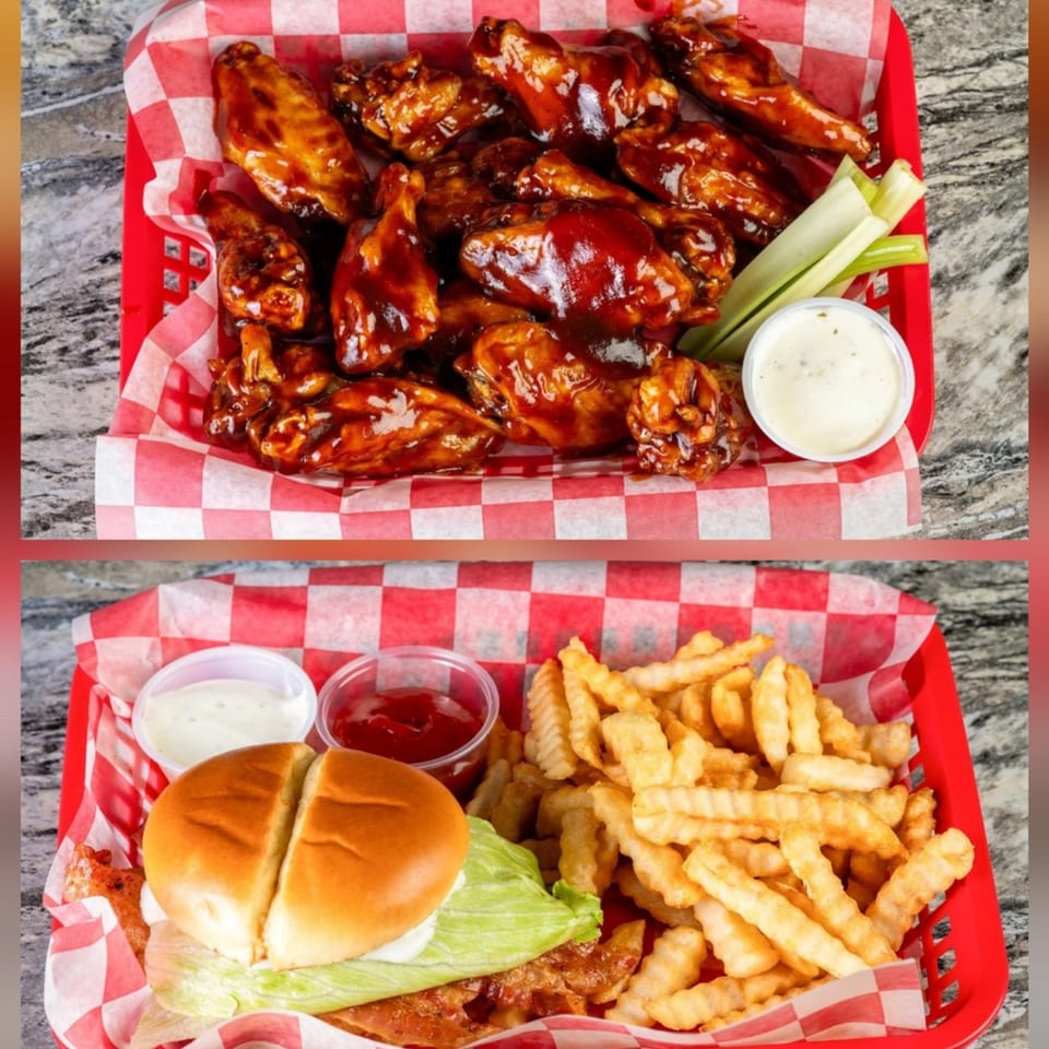 Two red baskets with checkered liners, one with BBQ wings, celery, and ranch, the other with a burger and fries.